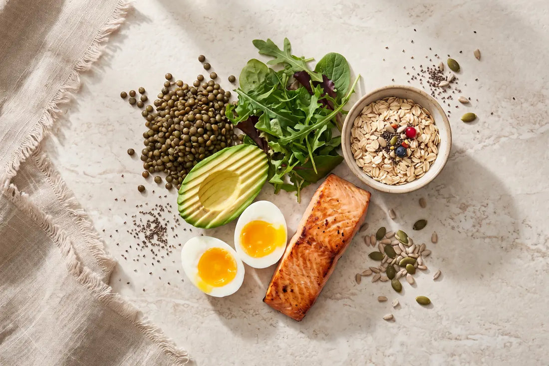 Overhead plate of protein- and fibre-rich whole foods — salmon, egg, lentils, avocado, greens and oats